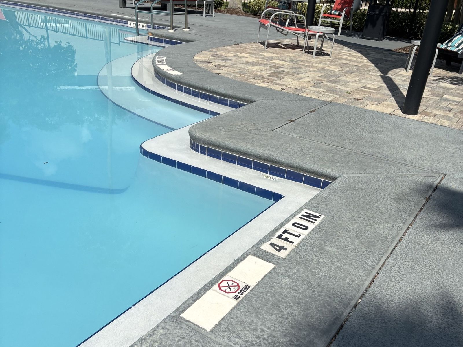Community pool with entry steps, depth markers and no-diving signs