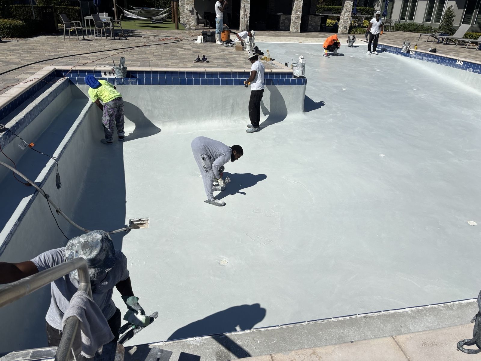 Crew finishing the floor and walls of a drained community pool
