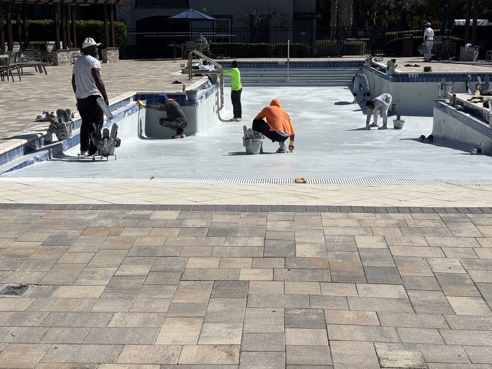 Playwell crew applying a new interior finish in a drained community pool